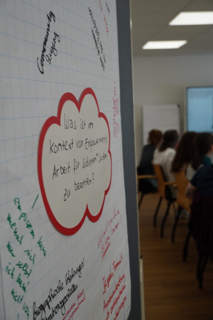 Flipchart mit der Frage „Was ist im Kontext von Empowerment Arbeit für die anderen* zu beachten?“ im Klassenzimmer
